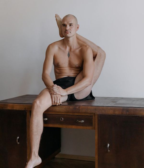 Man performing a slow, controlled strength exercise in a minimalist studio.